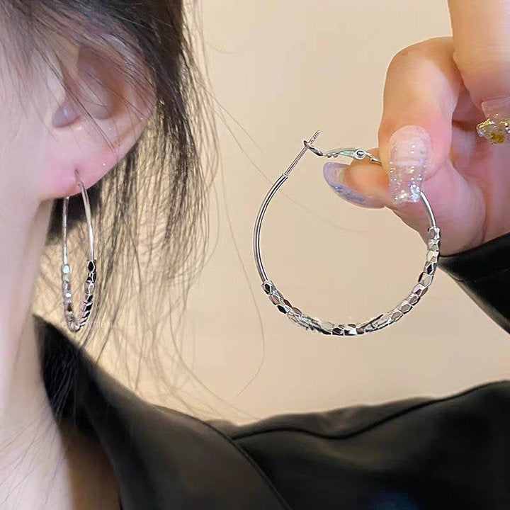 A woman with plain hoop earrings
