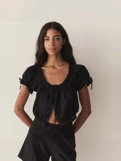 Puff-sleeve blouse with large round neckline, ruffled trim, and tie details