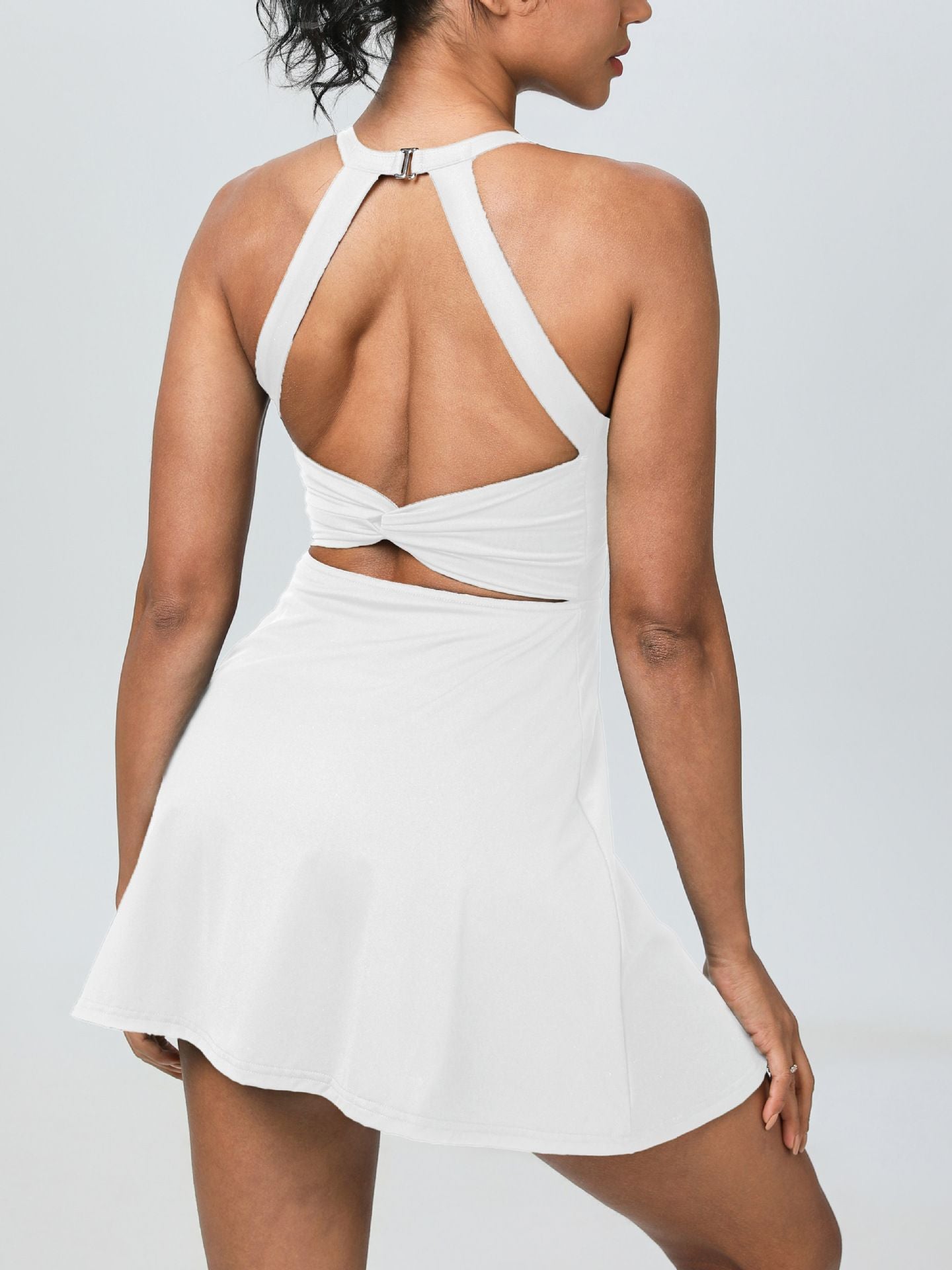 This backless sports dress features a short skirt with built-in shorts and is highly elastic